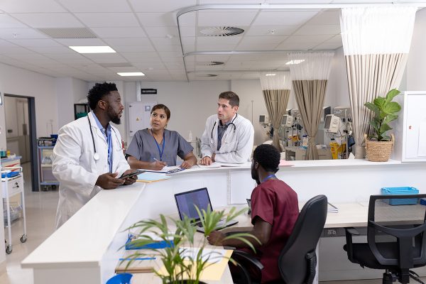 Diverse doctors and medical staff talking at reception desk of hospital ward. Hospital, teamwork, medical and healthcare services.